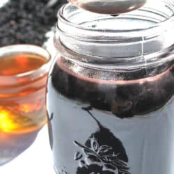 close up of homemade elderberry syrup in jar and on spoon