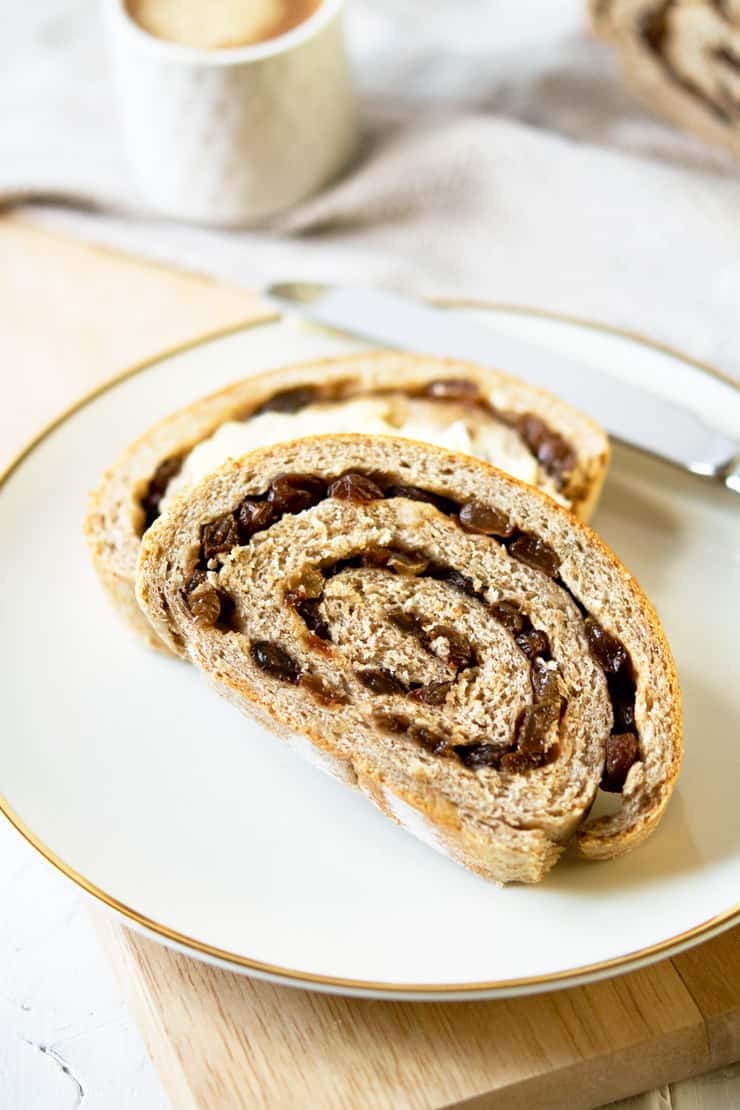 A close up of a slice of whole wheat cinnamon raisin bread on a white plate