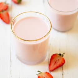 Two glasses of drinkable yogurt on a white wooden surface