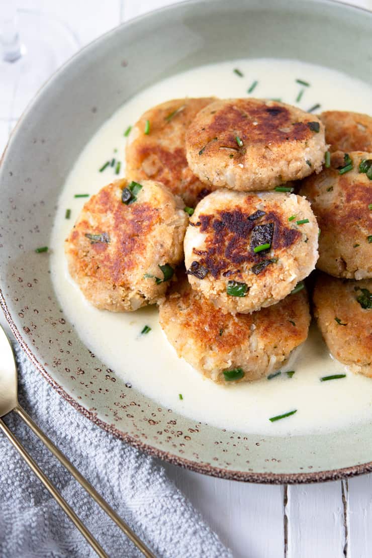 A side shot of crab cakes on a plate with wine and butter sauce