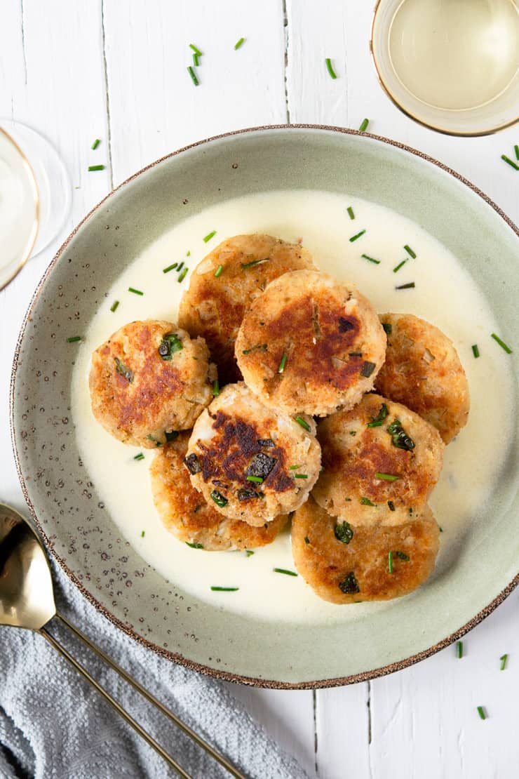 An overhead shot of crab cakes on a plate with a white wine sauce