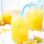 Two mason jars with natural pineapple lemonade and blue straws on a white surface