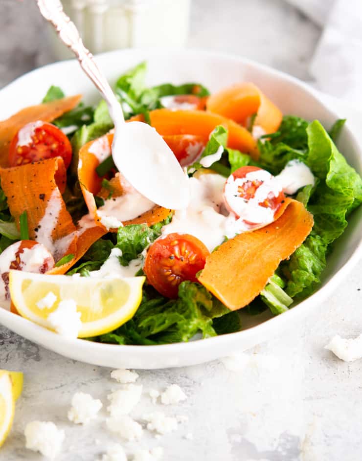 A salad with a creamy feta yogurt dressing drizzled over the top