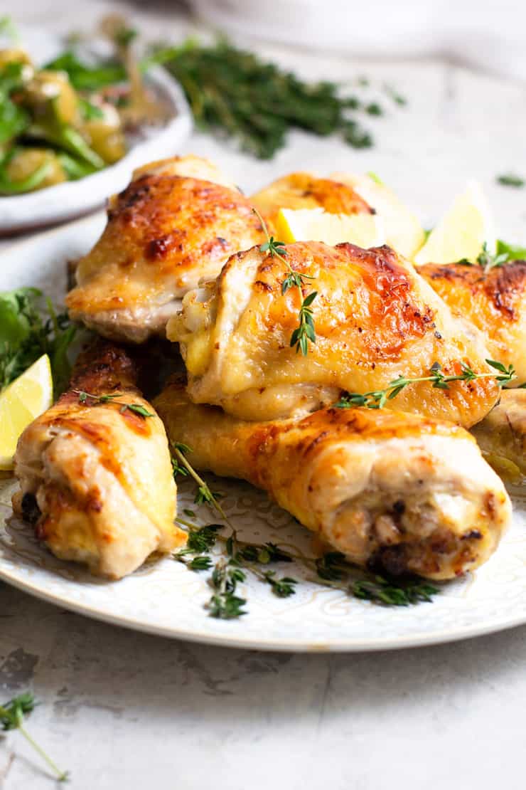 A close up of Greek chicken on a plate topped with fresh thyme