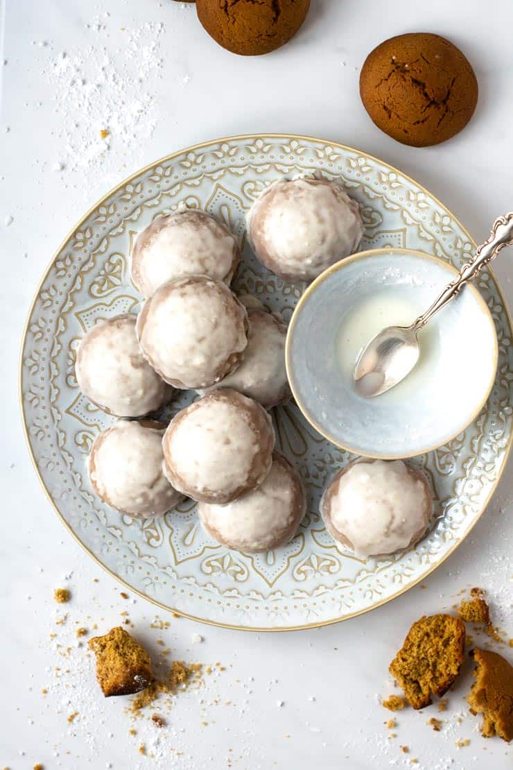 An overhead shot of ginger cookies on a plate with icing in a small bowl