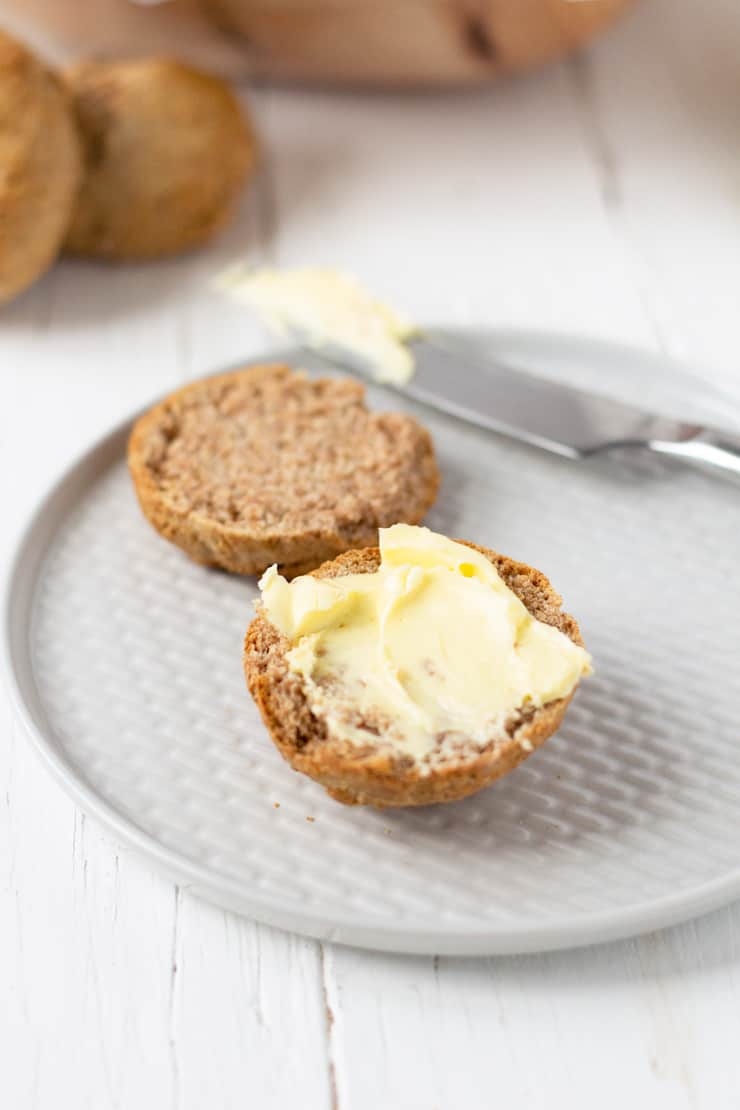 A drop biscuit cup in half spread with butter on a plate