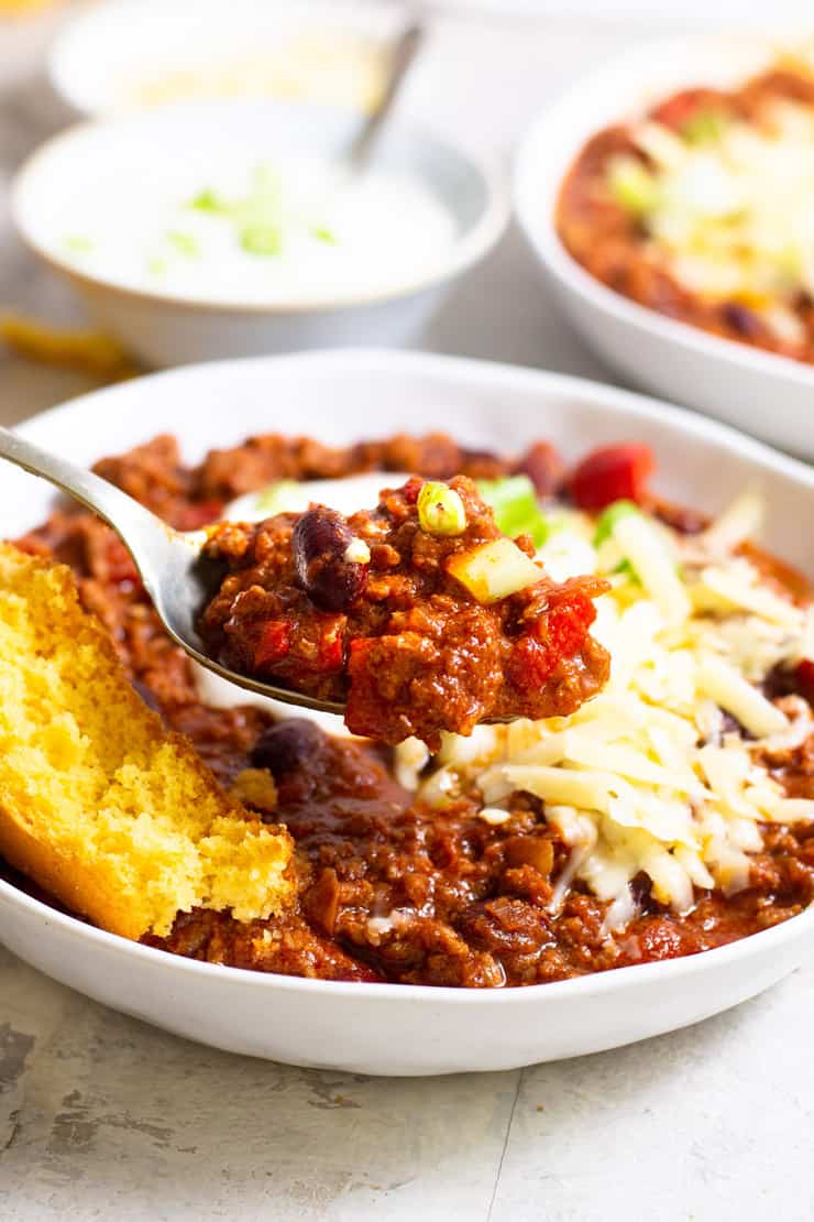 A close up of real texas chili in a bowl with a spoonful on a spoon