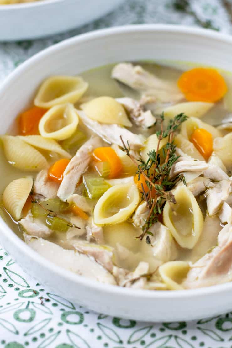 A close up of chicken noodle soup in a white bowl