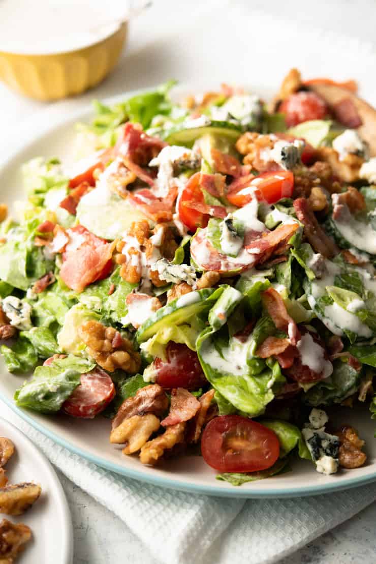 A close up of a blue cheese salad with bacon, walnuts and avocado