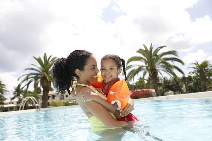 Portrait of smiling mother holding daughter in swimming pool