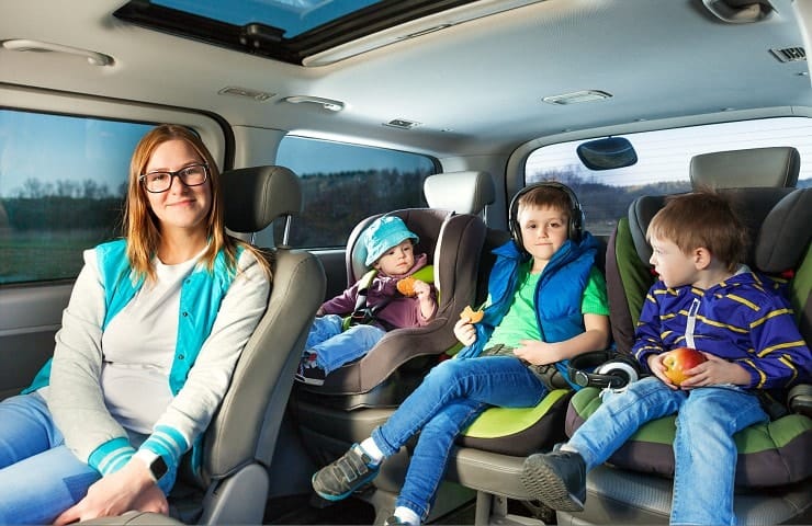 Mom and three kids in car seats for road trip