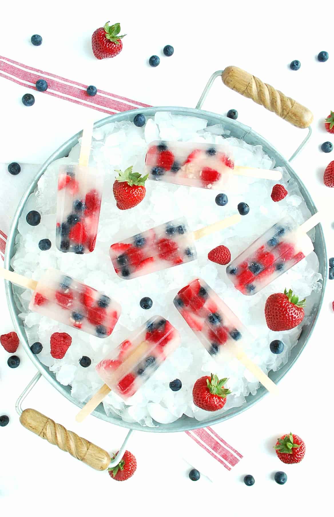 overhead shot of coconut water and fresh berry popsicles in a tray of ice