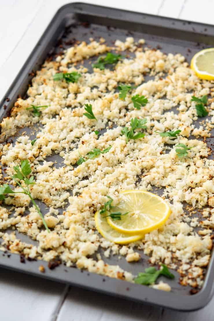 A tray of roasted cauliflower rice with slices of lemon