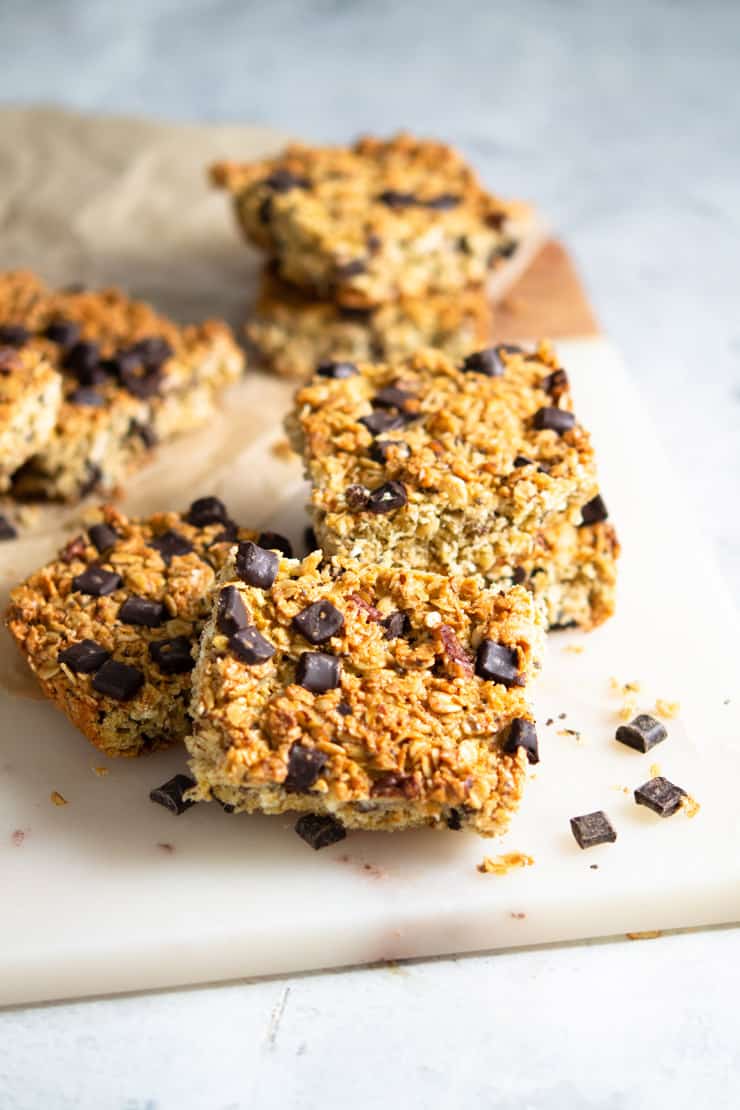 Chocolate chunk oatmeal bars on a marble cutting board with chocolate chunks scattered around