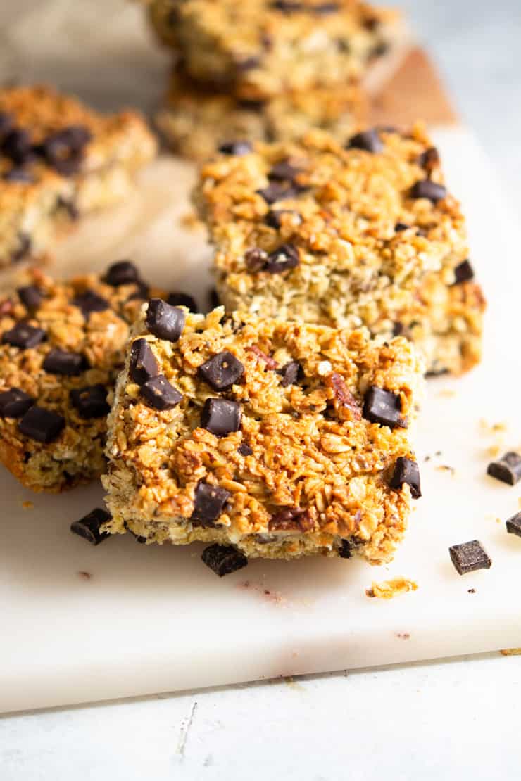 A close up of chocolate chunk oatmeal bars on a marble cutting board