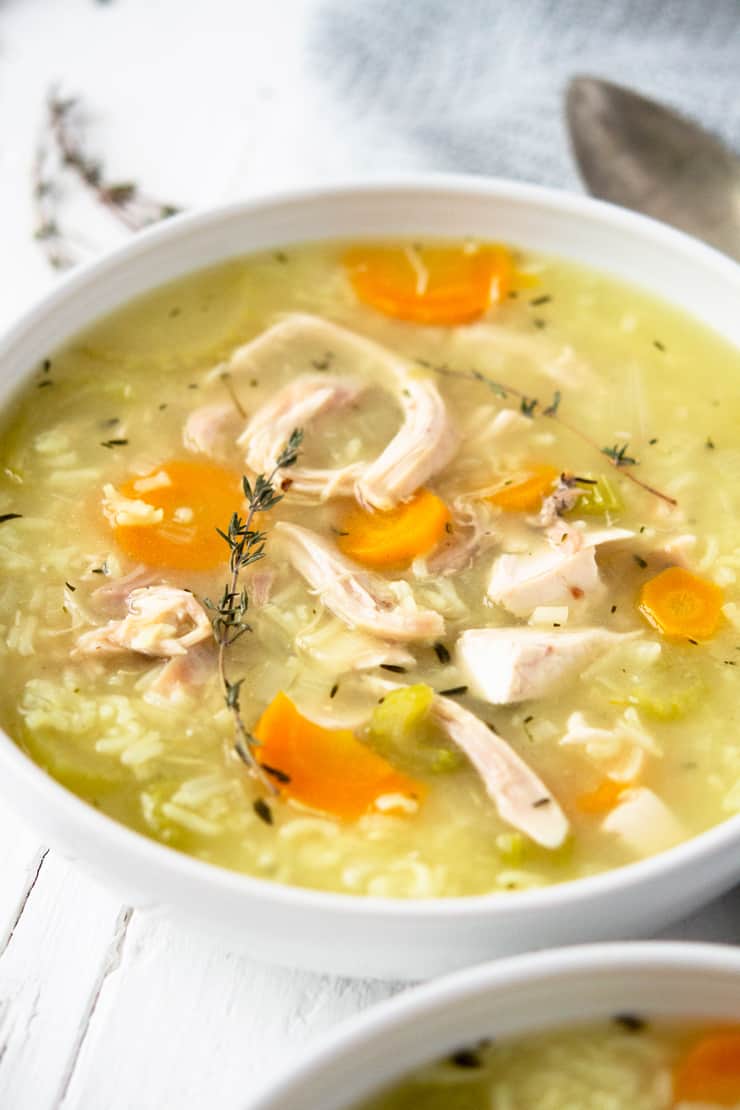 A close up of rotisserie chicken and rice soup in a white bowl 