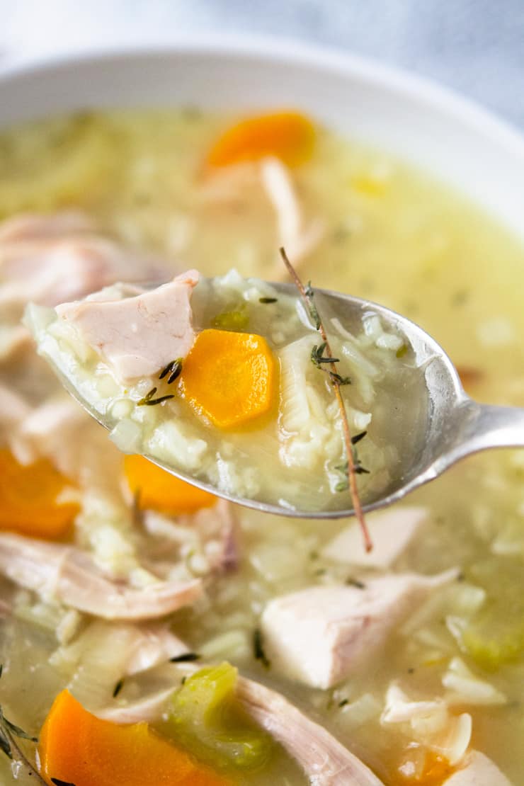 A close up of rotisserie chicken and rice soup on spoon 