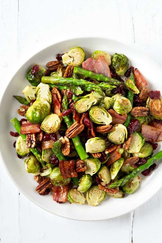 Roasted Brussels sprouts on a plate with asparagus, bacon and pecans