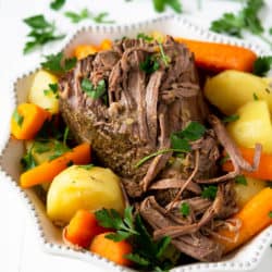 The Best Slow cooker beef roast in a white serving dish with vegetables