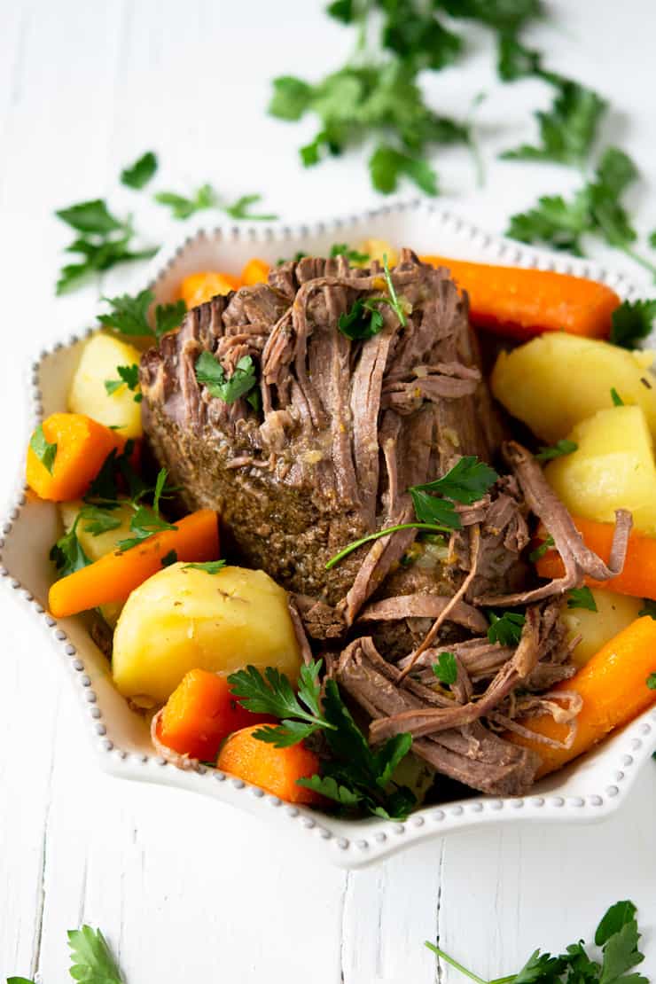 The Best Slow cooker beef roast in a white serving dish with vegetables