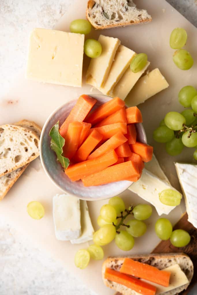 An overhead shot of fermented carrots on a cheeseboard