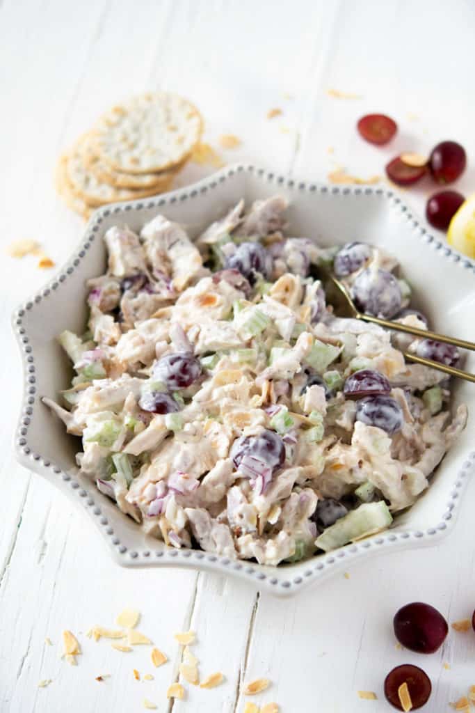 Rotisserie chicken salad in a white dish with grapes and crackers