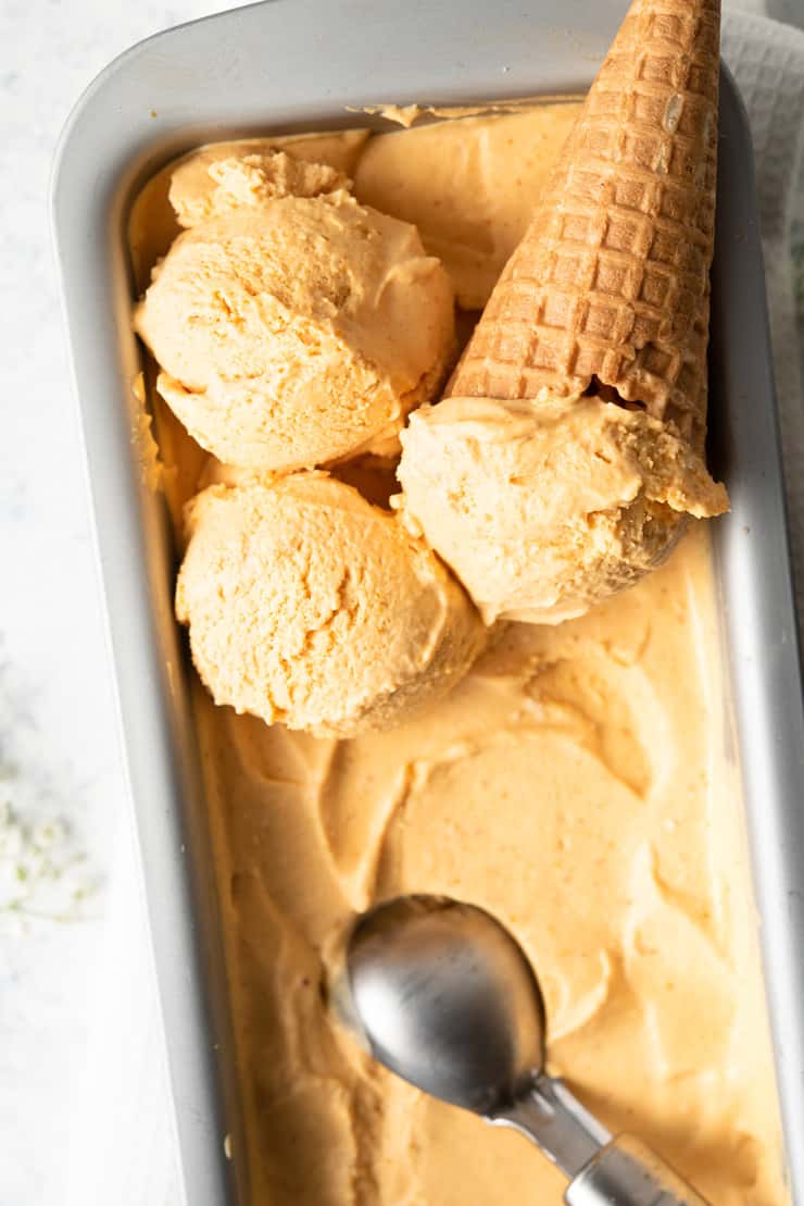A close up of no churn pumpkin ice cream in scoops with a cone