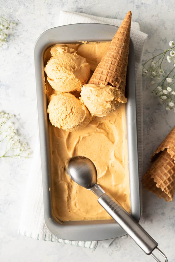 An overhead shot of a pumpkin ice cream in a loaf tin with scoops on top