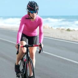 woman cyclist riding a bike on the road close to sea
