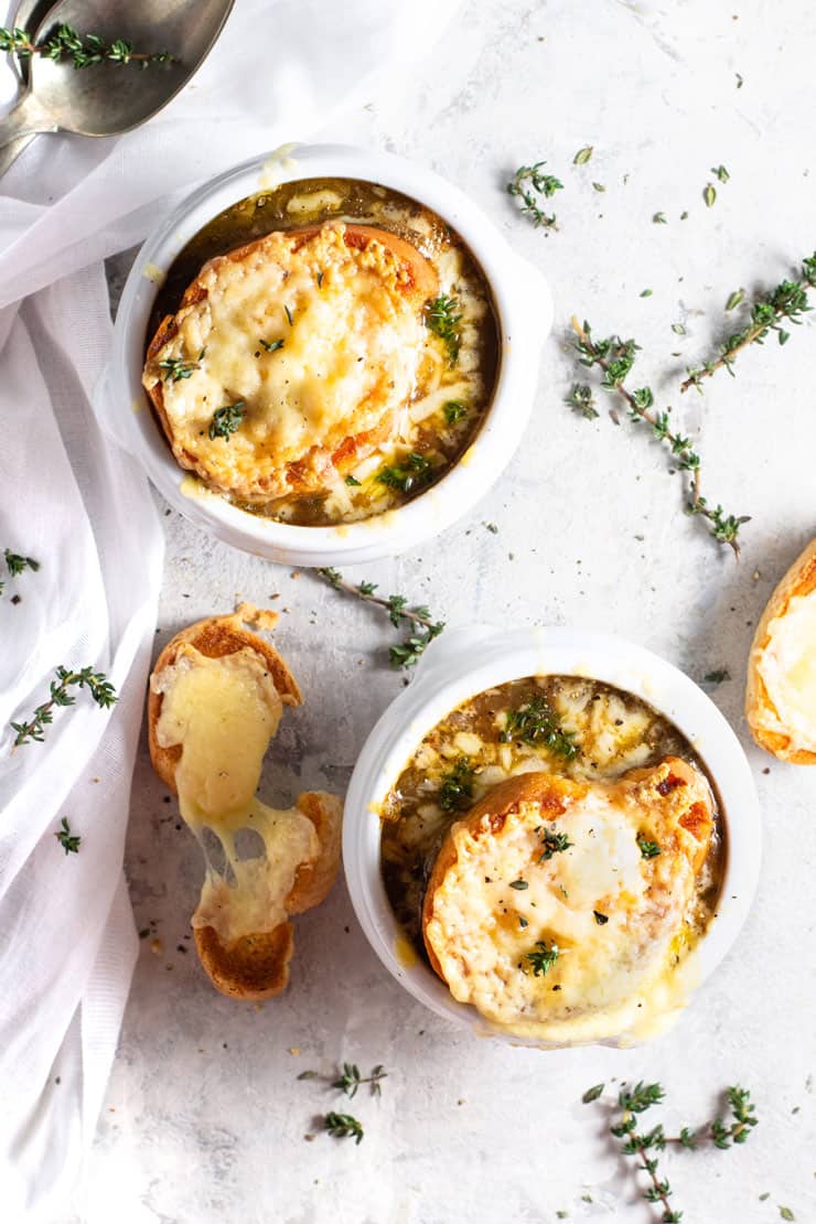 An overhead shot of french onion soup in two bowls topped with a slice of bread and melted cheese