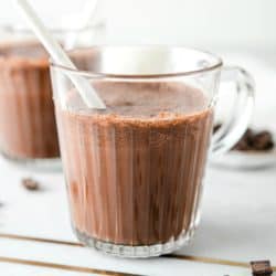Two glasses of healthy chocolate milk on a marble surface with white straws