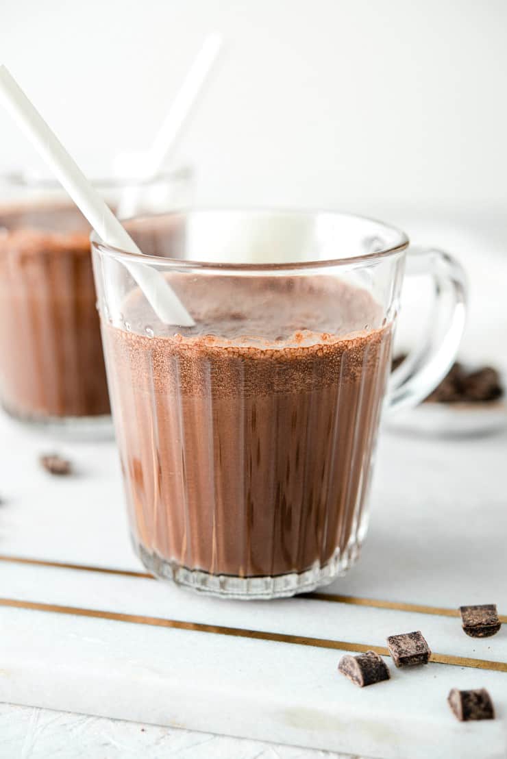 Two glasses of healthy chocolate milk on a marble surface with white straws