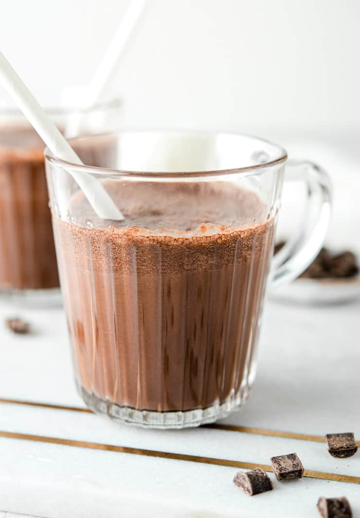 A close up of chocolate milk in a glass with a white straw