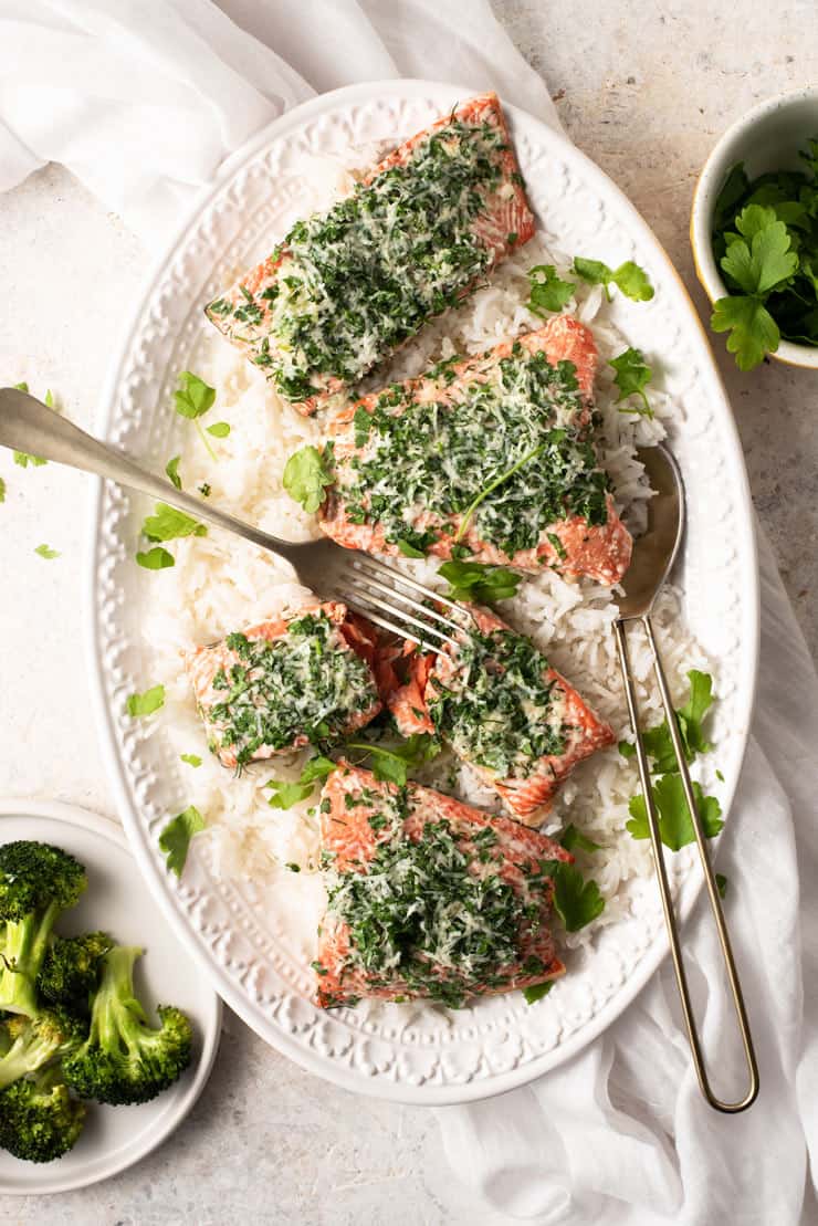 An overhead shot of baked salmon with parmesan crust on a serving platter with rice and broccoli