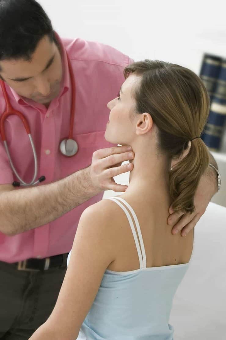 doctor examining woman's thyroid