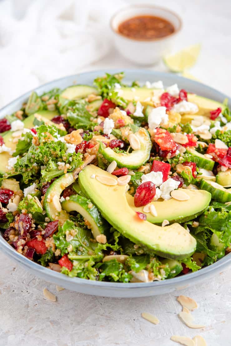 A side shot of a kale quinoa salad with avocado slices and feta