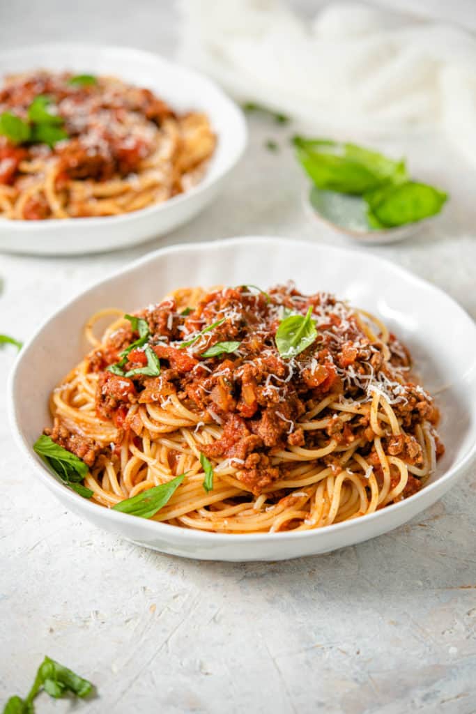 Slow cooker spaghetti sauce in a white bowl topped with basil