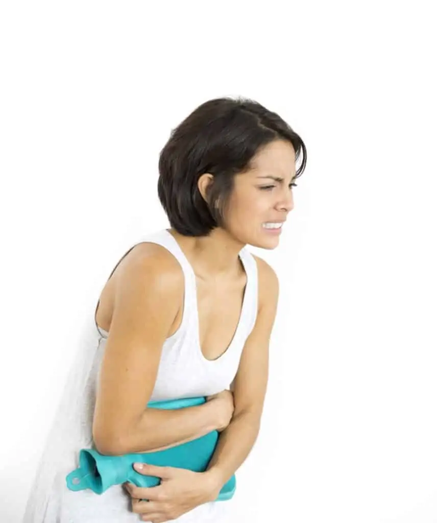 hispanic woman with PMS cramps holding heating pad over her stomach