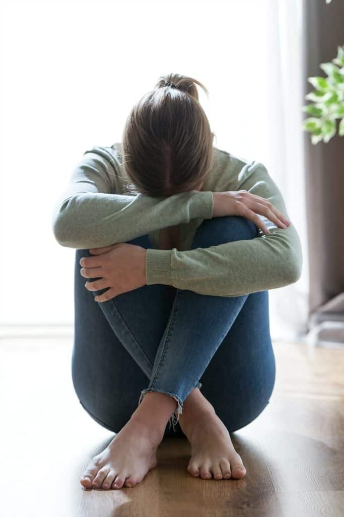 Discouraged woman sitting on floor with head in her hands