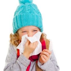 young girl in warm clothing blowing nose