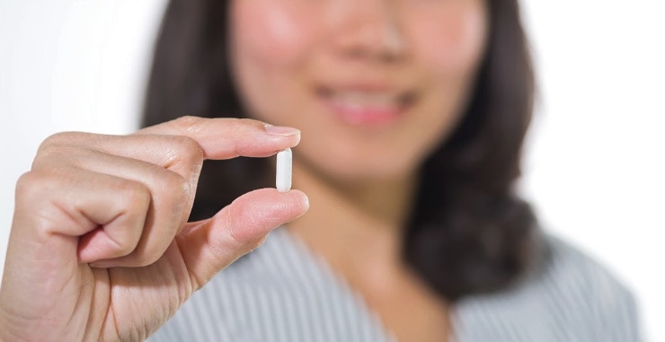 close up of woman holding white capsule