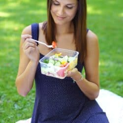 woman eating salad on picnic blanket