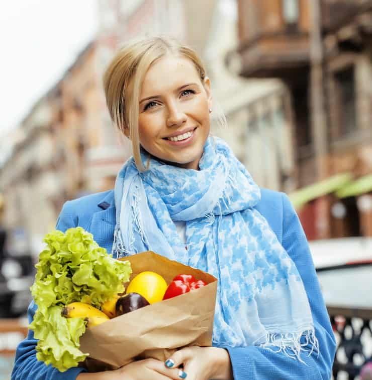 young blond woman with food in bag walking on street healthy cheerful