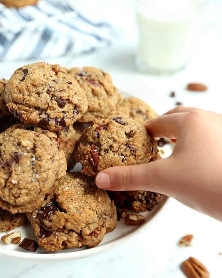 child's hand grabbing a chocolate chunk cookie from pile