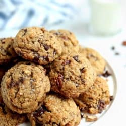 front view of pile of salted chocolate chunk cookies with pecan flour on a white cake stand