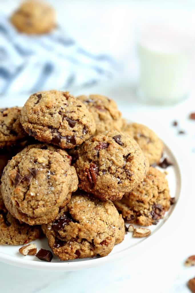 front view of pile of salted chocolate chunk cookies with pecan flour on a white cake stand