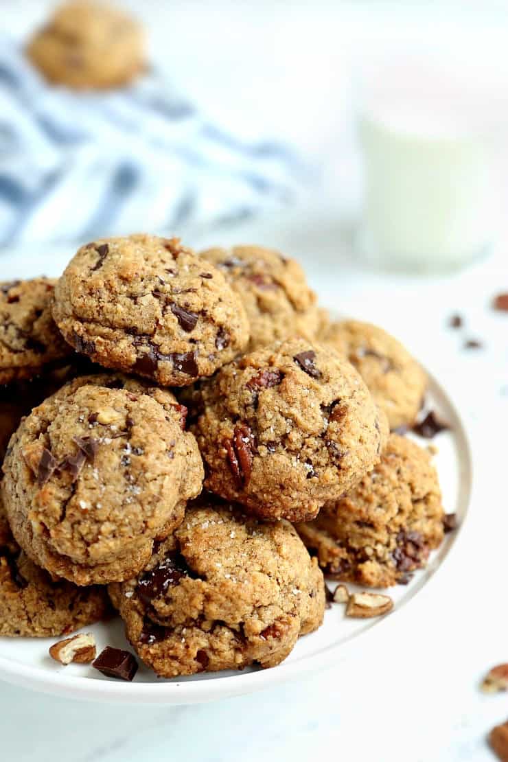 front view of pile of salted chocolate chunk cookies with pecan flour on a white cake stand