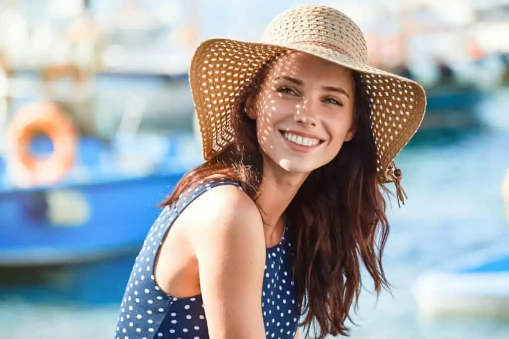 Beautiful brunette woman on boat dock wearing straw hat