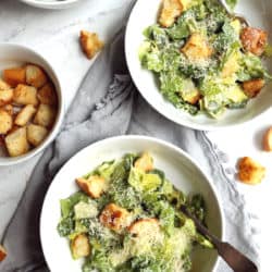 overhead view of Classic Caesar Salad with garlicky sourdough croutons in white bowls on marble background