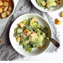 overhead shot of Classic Caesar salad in bowls with homemade croutons and text overlay with recipe title